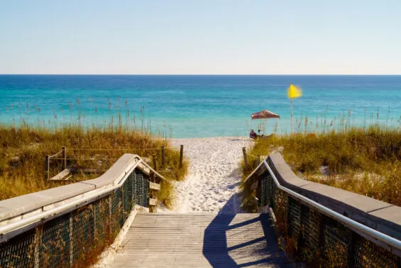 A boardwalk leads to white sand beach and blue water in Florida