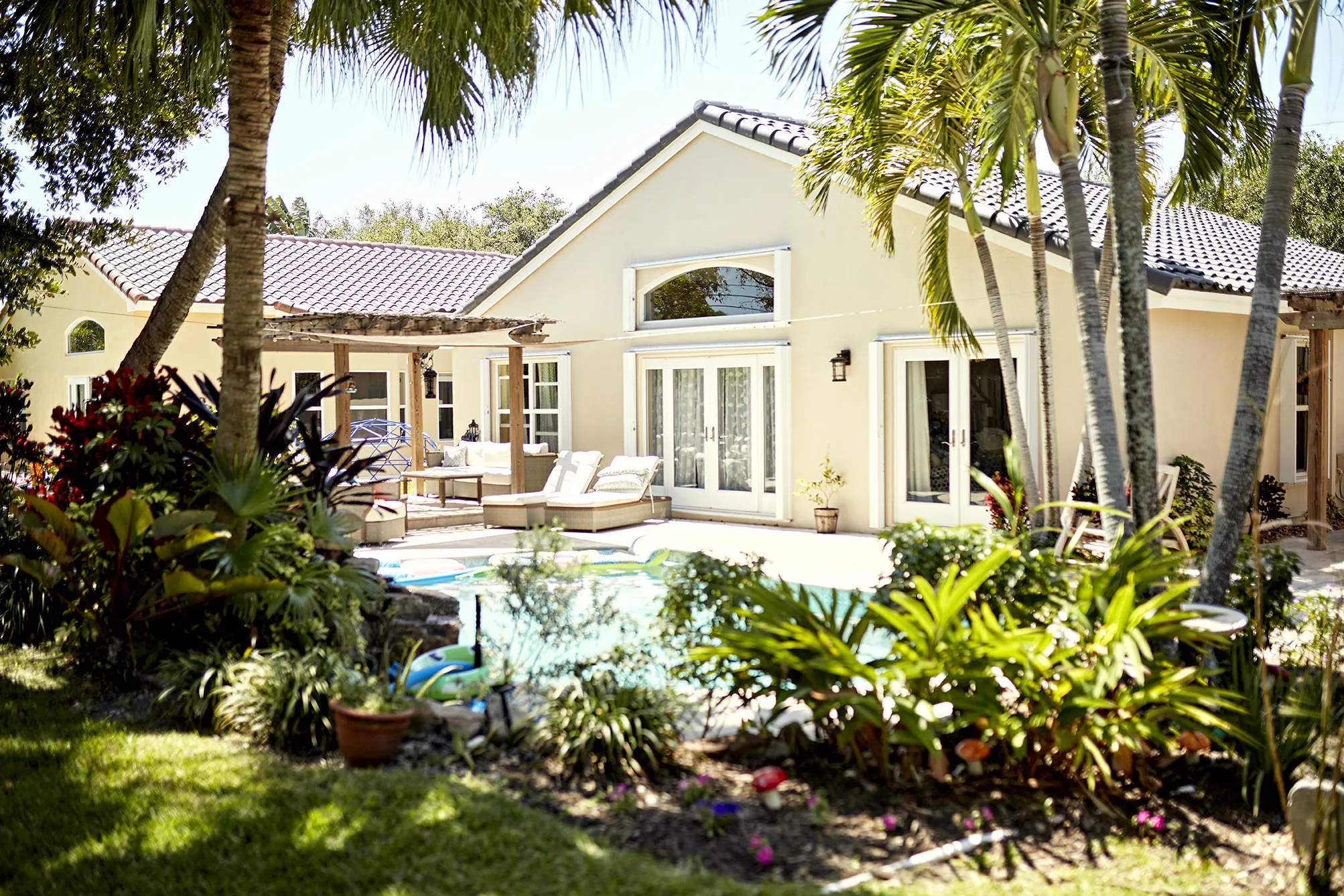 serene backyard of a family home in Florida with palm trees, beautiful landscaping and a small pool