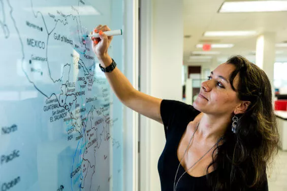 Woman marks a place on a dry-erase board map.